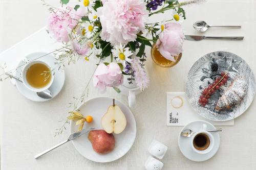 a table with plates of food and flowers and a cup of coffee at Hotel Luise in Riva del Garda
