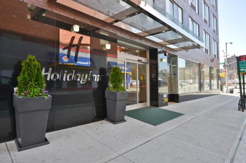 a store front with two potted plants on the sidewalk at Holiday Inn Lower East Side by IHG in New York