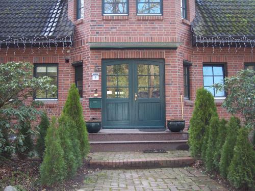 a brick house with a green door and stairs at Apartement in Siedlung Schönwalde