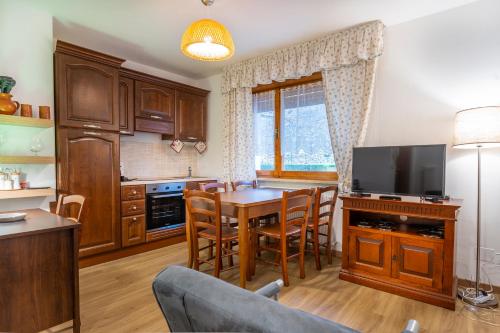 a kitchen with a dining room table with a tv at Moderno Appartamento Tarvisio - A due passi dalla Ciclovia! in Tarvisio