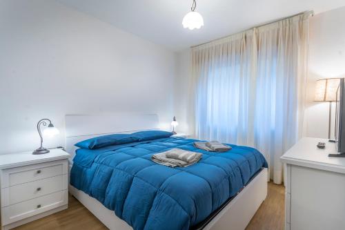 una camera bianca con un letto blu e una finestra di Moderno Appartamento Tarvisio - A due passi dalla Ciclovia! a Tarvisio