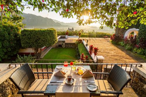 a table and chairs with a view of a garden at Posada del Tepozteco - Hotel & Gallery in Tepoztlán
