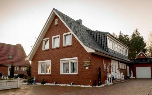 uma grande casa de tijolos vermelhos com um telhado preto em Ferienwohnung Schoon, 85042 em Ostrhauderfehn