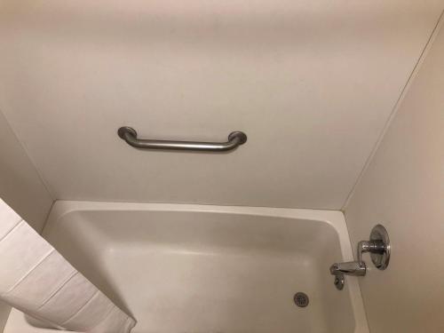 a bath tub in a bathroom with a metal handle at Days Inn by Wyndham Deming in Deming