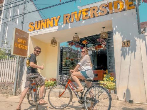 a man and a woman riding bikes in front of a shop at Sunny Riverside Homestay in Hoi An