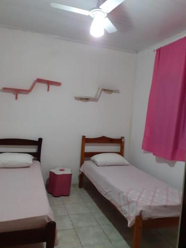 a room with two beds and a ceiling fan at Casa pra temporada in Prado