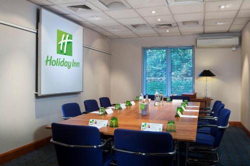 a conference room with a long table and blue chairs at Holiday Inn Oxford by IHG in Oxford
