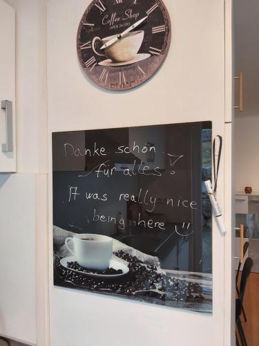 a sign on a wall with a clock and a cup at Relax-Apartment mit Sauna in Klagenfurt