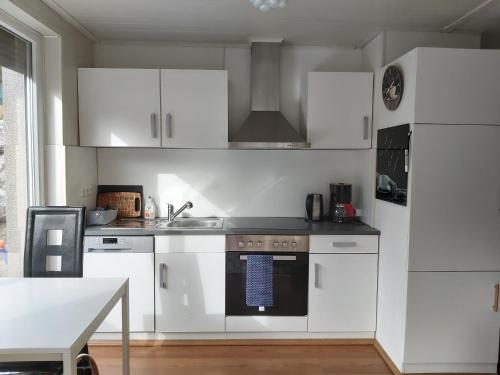 a kitchen with white cabinets and a sink and a stove at Relax-Apartment mit Sauna in Klagenfurt