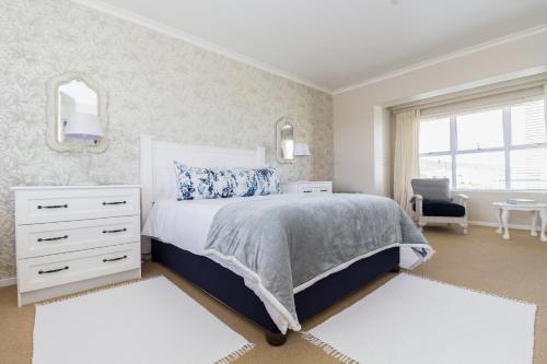a bedroom with a bed and a dresser and a window at South Point Guest Lodge in Agulhas