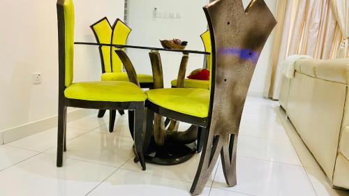 una mesa de comedor con sillas amarillas junto a un sofá en Shortlethomes, en Maiyegun