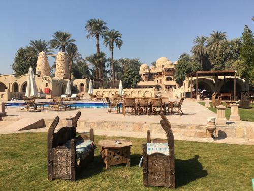 a park with chairs and tables in front of a pool at Djorff Palace in Luxor