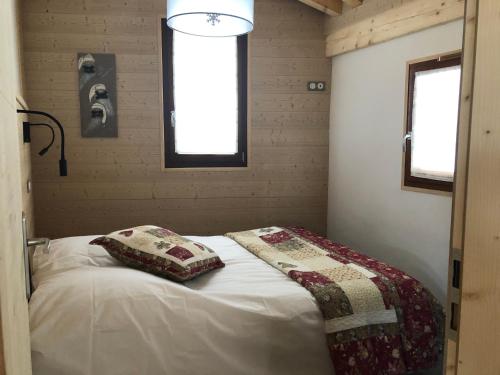 モルジヌにあるChalet Croq'Neigeの小さなベッドルーム(白いシーツと枕のベッド付)