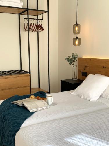 a bed with a book and a cup and a teddy bear at Hotel Boutique Astorga in Valladolid