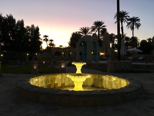 a yellow fountain in front of a building at sunset at Djorff Palace in Luxor