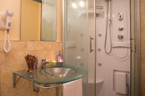 カターニアにあるB&B テアトロ ベリーニのバスルーム(ガラスの洗面台、シャワー付)