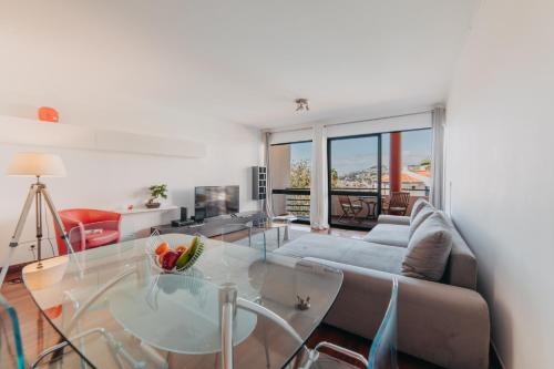 a living room with a glass table and a couch at Funchal Lounge Apartment by Amazing Madeira in Funchal