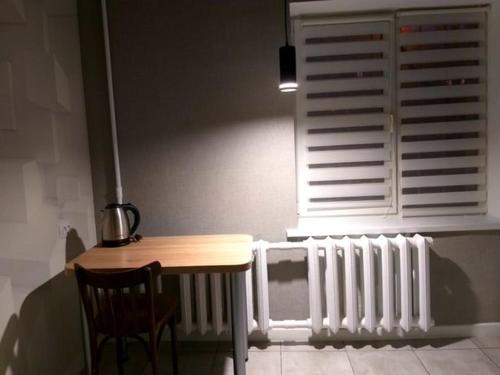 einem Tisch und Stuhl neben einem Heizkörper und einem Fenster in der Unterkunft Тихий lux, левый берег, Караван in Nizhnedneprovsk