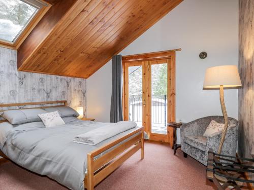 a bedroom with a bed and a chair and a window at Torbreck Chalet in Kingussie
