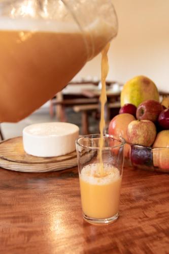 a person pouring an orange juice into a glass at Espaco Morro do Frota in Pirenópolis