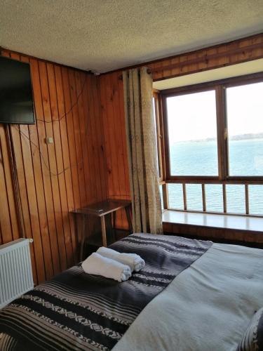 a bedroom with two beds and a large window at Laguneclub - Su casa de campo in Frutillar