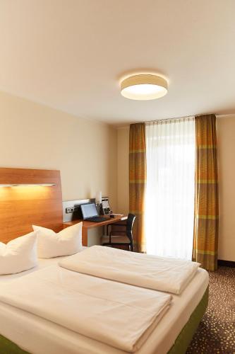 a hotel room with two beds and a desk at Hotel Restaurant Erber in Ismaning