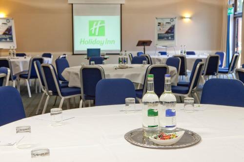 a room with tables and chairs with bottles and a bowl of food at Holiday Inn Haydock by IHG in Haydock