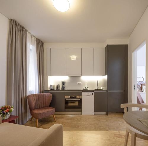 a kitchen with white cabinets and a living room at Lisbon Serviced Apartments - Santos in Lisbon