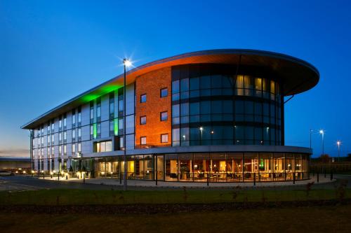 a large building with a building at night at Holiday Inn Salisbury - Stonehenge by IHG in Salisbury