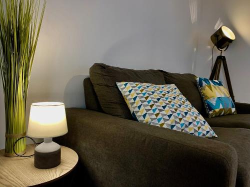 a brown couch with pillows and a lamp on a table at La charmeraie in Compiègne