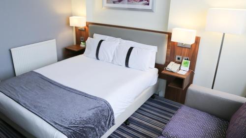 a hotel room with a bed and a phone at Holiday Inn Runcorn M56 Junction 12 by IHG in Runcorn