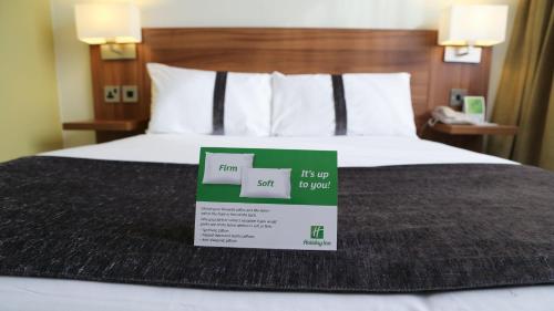 a hotel room with a bed with a sign on it at Holiday Inn Runcorn M56 Junction 12 by IHG in Runcorn