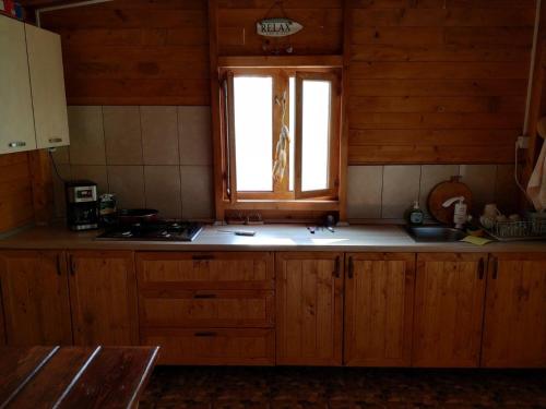 a kitchen with wooden cabinets and a window at Casa Ina in Sfântu Gheorghe