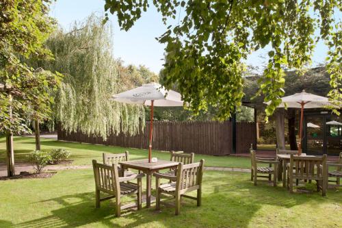 a table and chairs with an umbrella in a yard at Holiday Inn Runcorn M56 Junction 12 by IHG in Runcorn