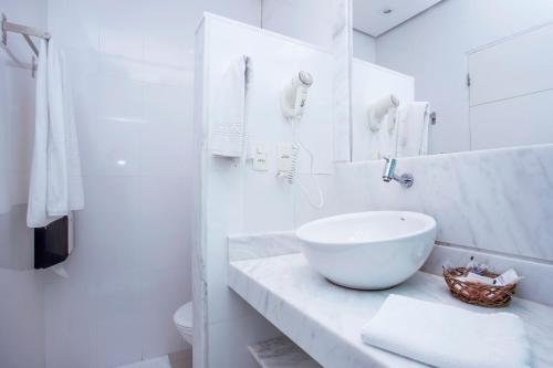 a white bathroom with a bowl sink on a counter at Hotel Ilhabela in Ilhabela