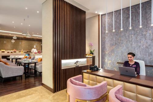 a woman sitting at a desk with a laptop in a restaurant at Crowne Plaza Bahrain by IHG in Manama