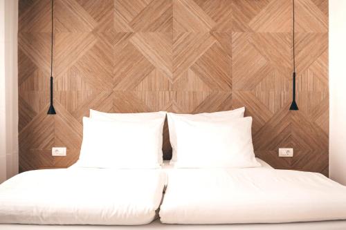 two beds with white sheets and wooden wall at City Apartment One in Mostar