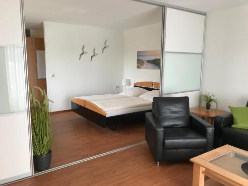 シュタインにあるSteiner Strandappartements Appartement 210 Südseite mit seitlichem Meerblickのベッドルーム1室(ベッド1台、ソファ、椅子付)