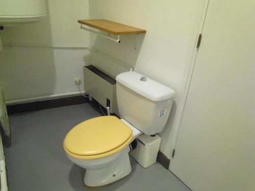 a bathroom with a toilet with a yellow lid at Le trou dans le mur in Uzerche