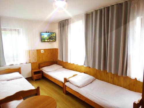 Una habitación con tres camas y un televisor en la pared. en Ośrodek Wczasowy Zielona Gospoda, en Przesieka
