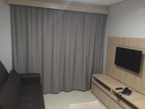 a hotel room with a television and a living room at Apartamento no Condomínio Casa da Madeira em Caldas Novas-GO in Caldas Novas