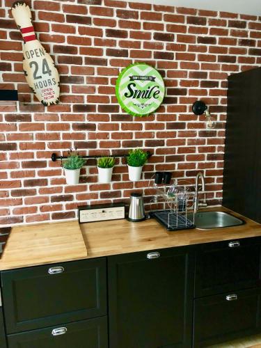 a kitchen with a sink and a brick wall at La charmeraie in Compiègne