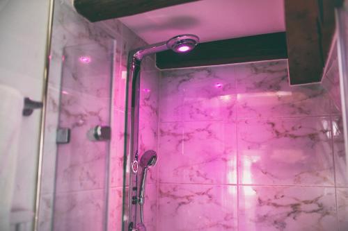 ein rosafarbenes Badezimmer mit einer Dusche mit rosa Lichtern in der Unterkunft Restaurant Residence Ente in Biberach an der Riß