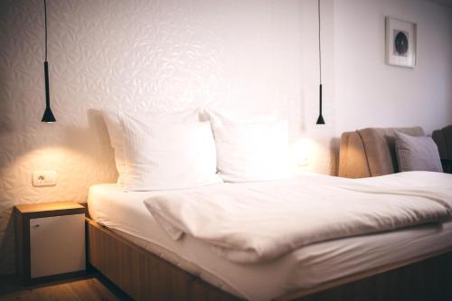 a bedroom with a bed with white sheets and pillows at City Apartment One in Mostar