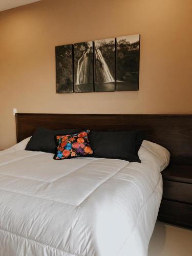 um quarto com uma cama branca e duas fotografias na parede em Suites Santiago em Santiago