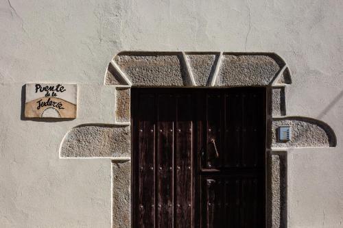 una puerta con una señal en el lateral de un edificio en Apartamentos Puente de la Judería en Hervás