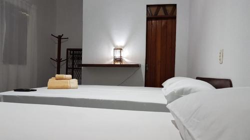 um quarto branco com 2 camas e uma luz sobre uma mesa em Casa Antiga Hospedagem em Barra Grande