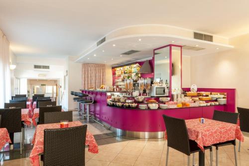 ein Restaurant mit einer lila Theke mit Tischen und Stühlen in der Unterkunft Augustus Hotel in Biella