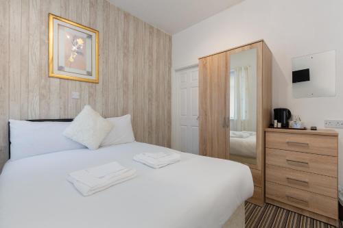 a bedroom with a white bed and a wooden cabinet at The Sandringham Court Hotel & Apartment Welcoming Large and Small Groups for 16 years in Blackpool