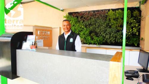 Un uomo in piedi dietro un bancone con un muro verde di Terra Suites Ecogreen a Tacna